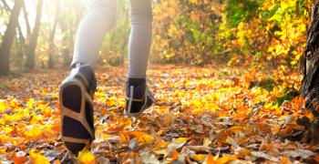 Pige løber i skov i efterårsfarver