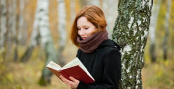 pige læser i bog ude i en skov
